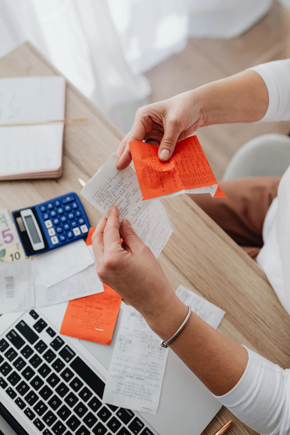 Receipts being sorted next to a calculator and laptop
